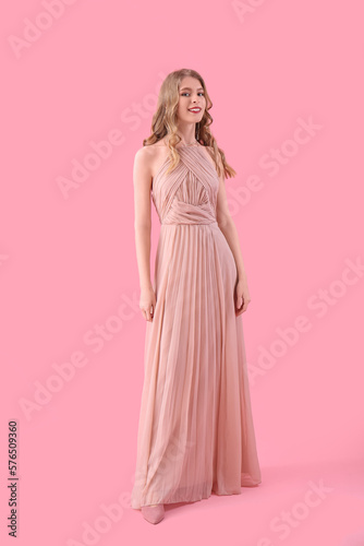 Teenage girl in prom dress on pink background