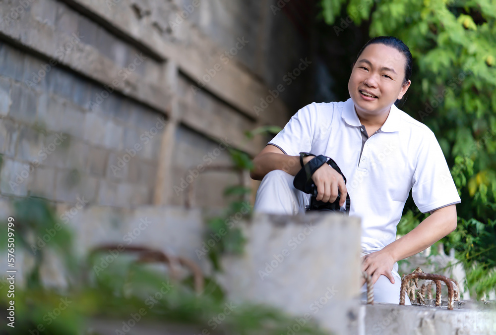 Asian Professional cameraman sits and thinks about how to create a creativity photo in the construction area background and environment. Asian Professional cameraman sits and thinks about how to create a creativity photo in the construction area background and environment.