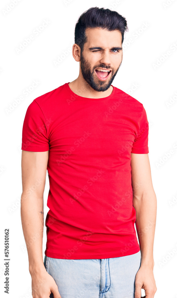 Obraz premium Young handsome man with beard wearing casual t-shirt winking looking at the camera with sexy expression, cheerful and happy face.