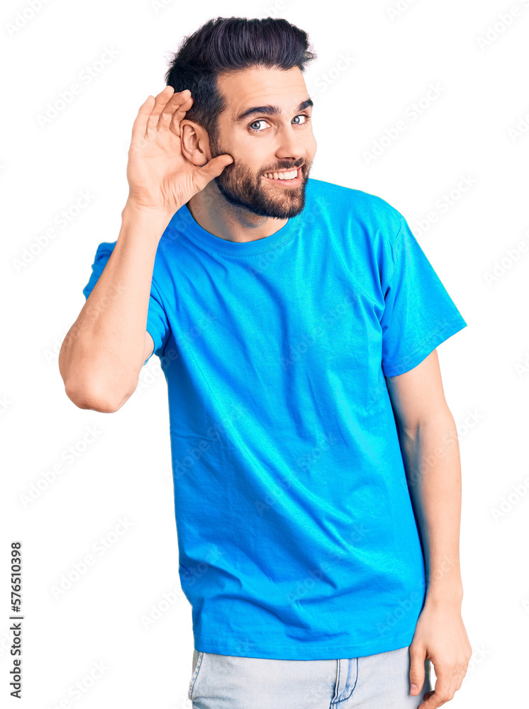 Young handsome man with beard wearing casual t-shirt smiling with hand over ear listening an hearing to rumor or gossip. deafness concept. Young handsome man with beard wearing casual t-shirt smiling with hand over ear listening an hearing to rumor or gossip. deafness concept.