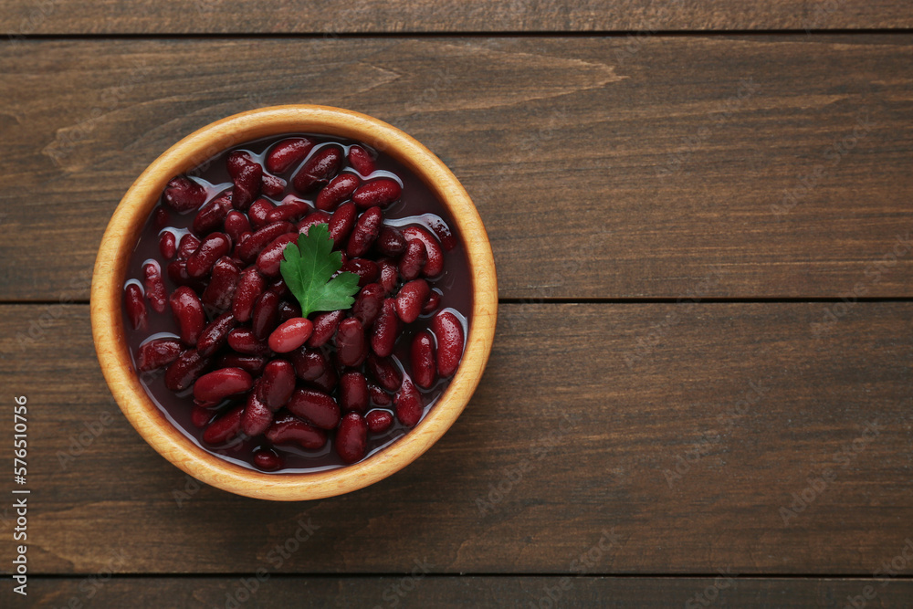 Bowl of canned red kidney beans with parsley on wooden table, top view. Space for text Bowl of canned red kidney beans with parsley on wooden table, top view. Space for text