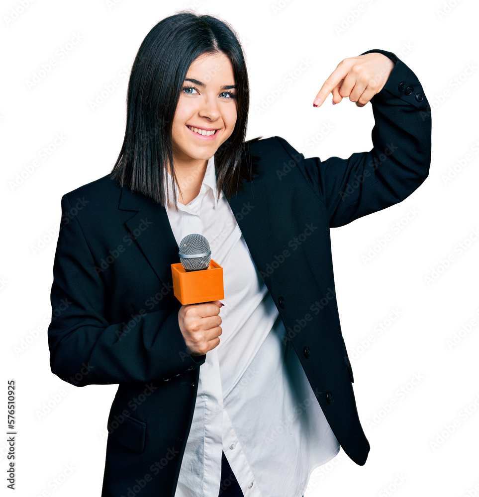 Young brunette woman with blue eyes holding reporter microphone pointing finger to one self smiling happy and proud Young brunette woman with blue eyes holding reporter microphone pointing finger to one self smiling happy and proud