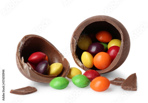 Tasty broken chocolate egg with colorful candies isolated on white