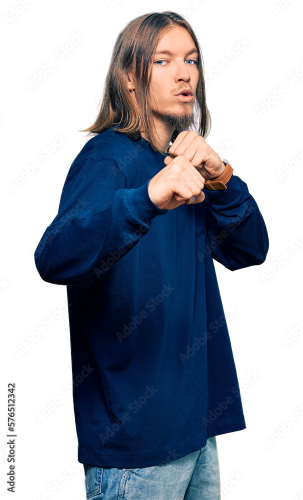Handsome caucasian man with long hair wearing casual winter sweater ready to fight with fist defense gesture, angry and upset face, afraid of problem Handsome caucasian man with long hair wearing casual winter sweater ready to fight with fist defense gesture, angry and upset face, afraid of problem