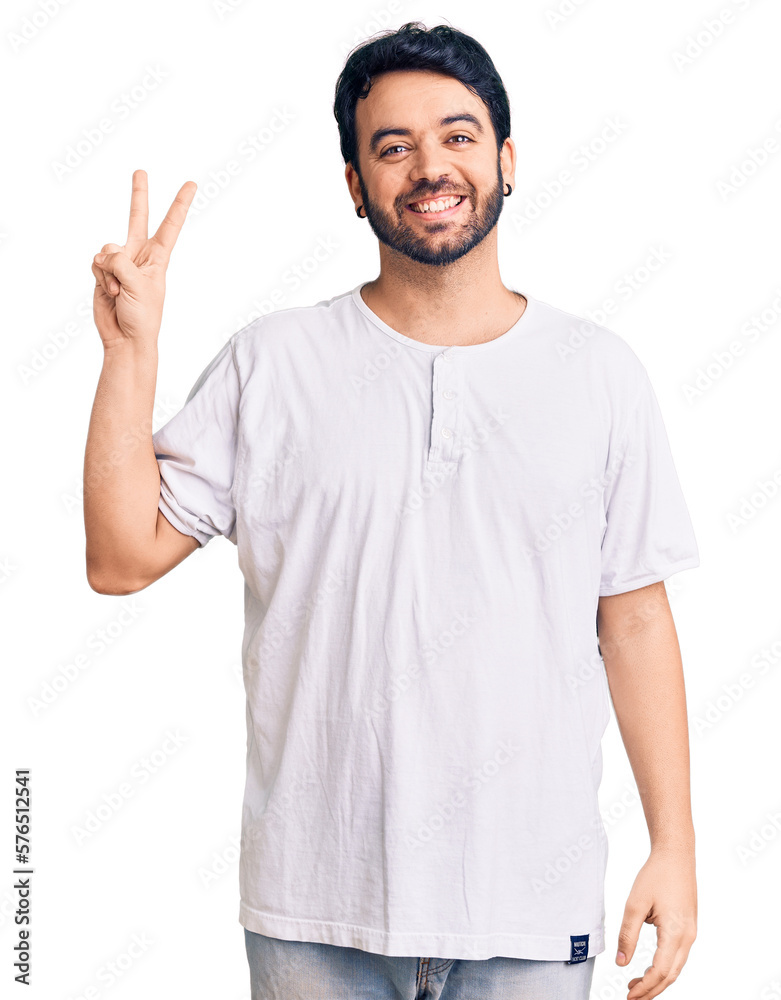 Young hispanic man wearing casual clothes smiling with happy face winking at the camera doing victory sign. number two. Young hispanic man wearing casual clothes smiling with happy face winking at the camera doing victory sign. number two.