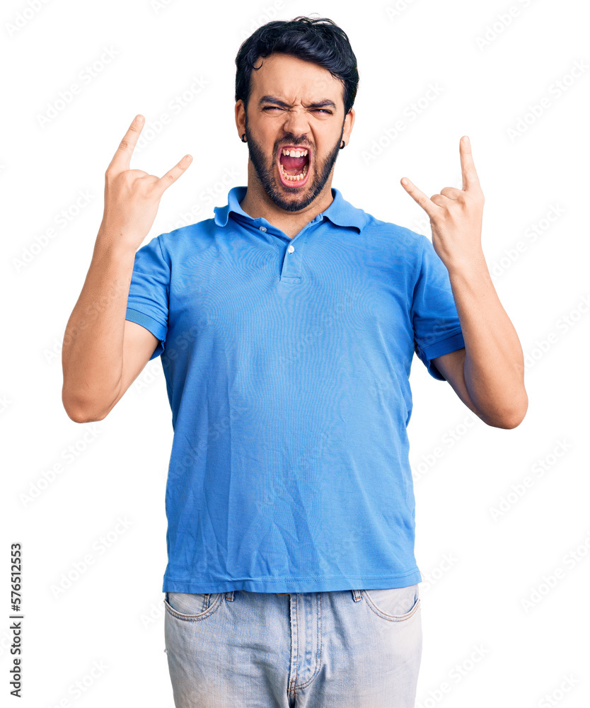 Naklejka premium Young hispanic man wearing casual clothes shouting with crazy expression doing rock symbol with hands up. music star. heavy concept.