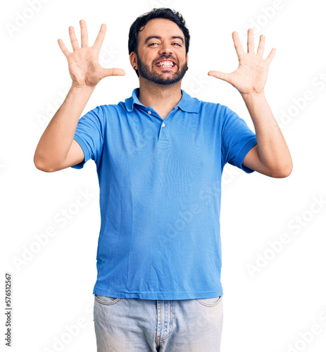 Young hispanic man wearing casual clothes showing and pointing up with fingers number ten while smiling confident and happy.