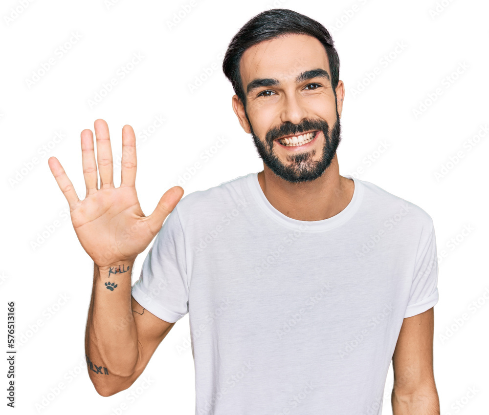 Naklejka premium Young hispanic man wearing casual white t shirt showing and pointing up with fingers number five while smiling confident and happy.