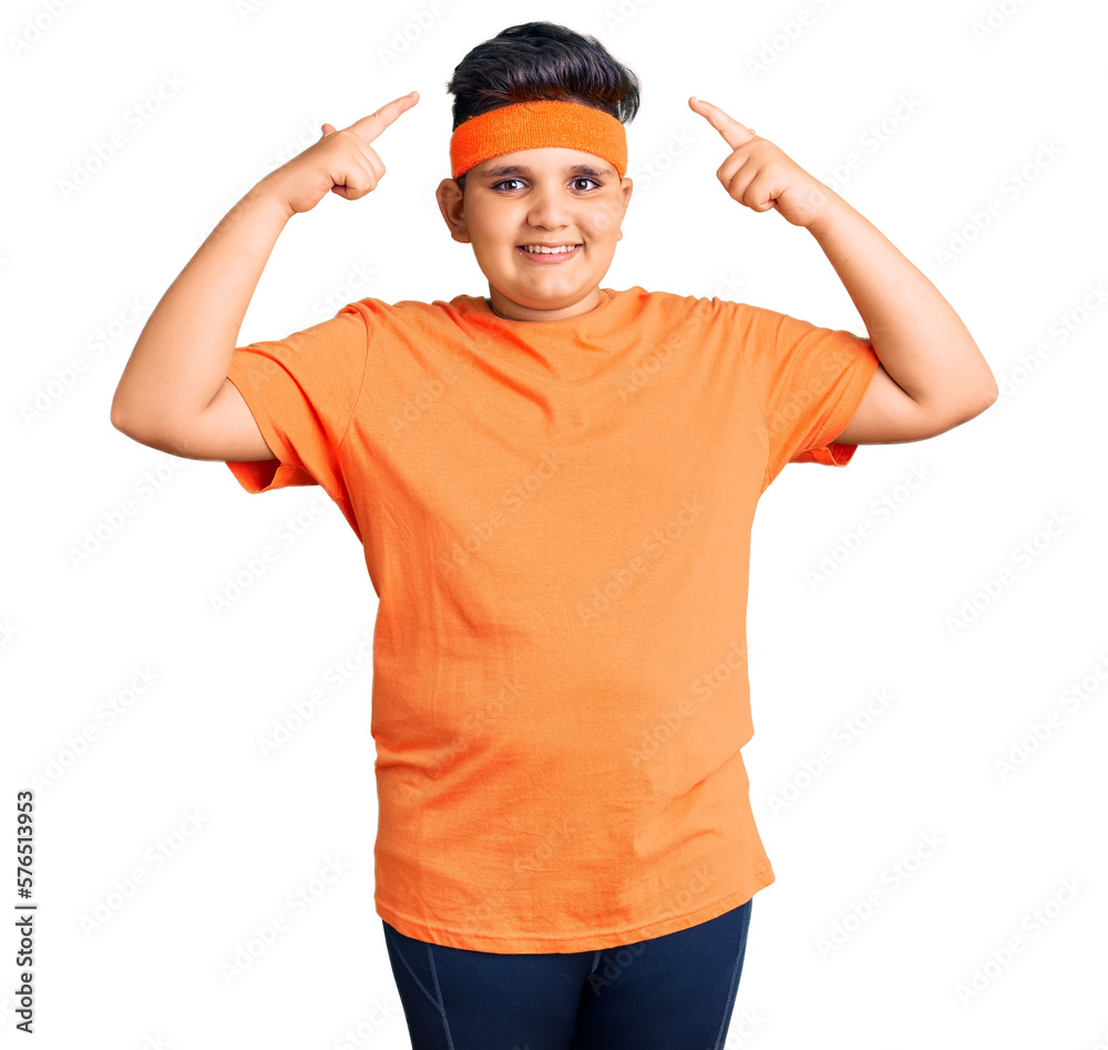 Little boy kid wearing sportswear smiling pointing to head with both hands finger, great idea or thought, good memory Little boy kid wearing sportswear smiling pointing to head with both hands finger, great idea or thought, good memory