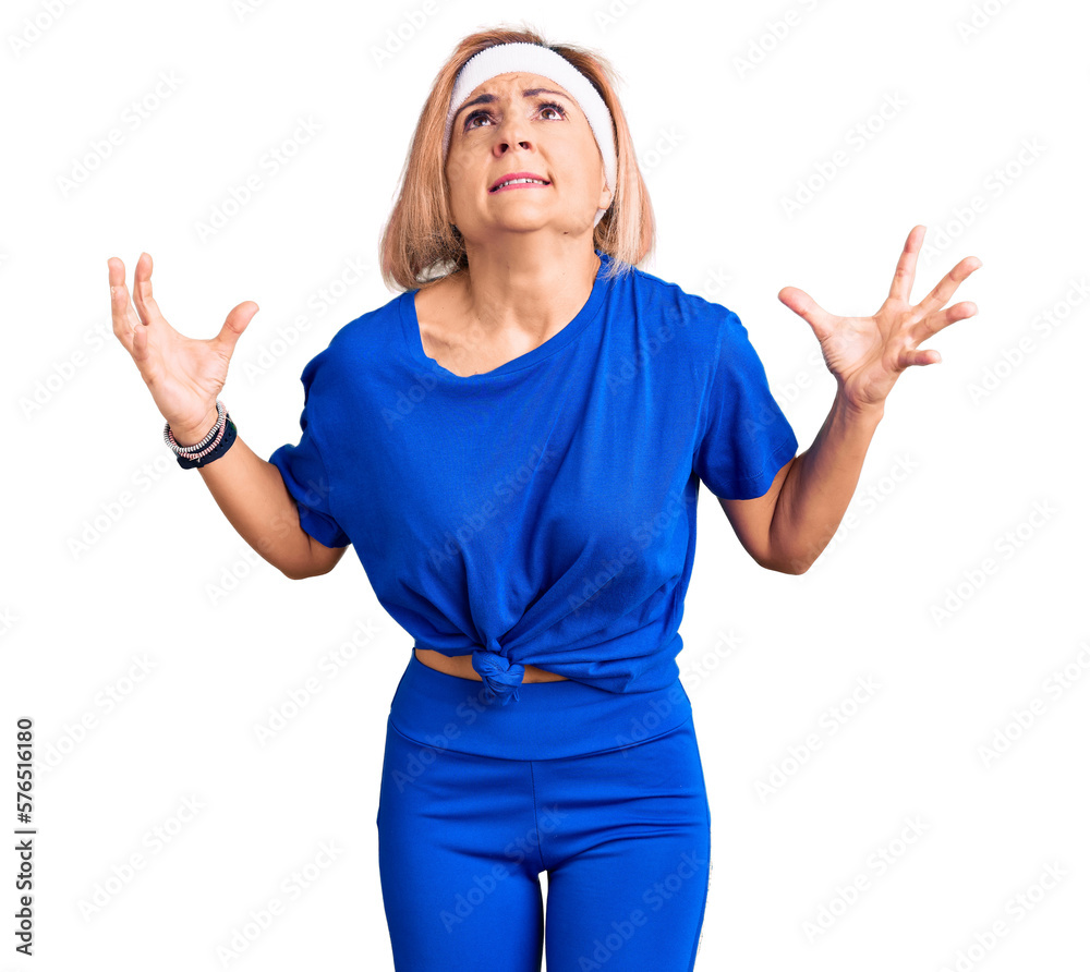 Young blonde woman wearing sportswear crazy and mad shouting and yelling with aggressive expression and arms raised. frustration concept. Young blonde woman wearing sportswear crazy and mad shouting and yelling with aggressive expression and arms raised. frustration concept.