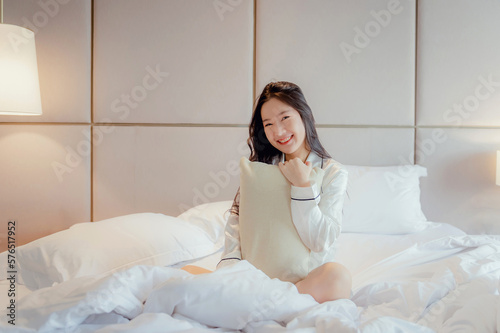 Asian teenage girl resting on the mattress After a full night's sleep And working in the morning in the bedroom. She is cheerful, bright, and happy.