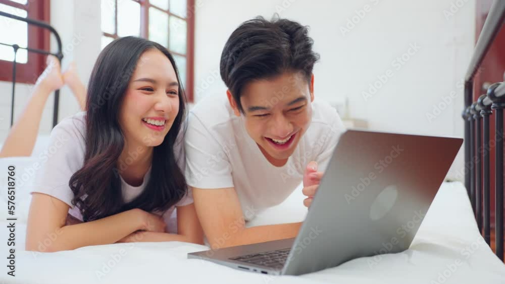 Asian attractive woman using laptop on bed with husband in the morning