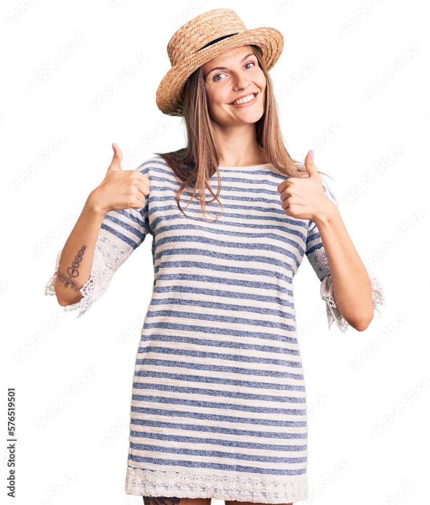 Beautiful caucasian woman wearing summer hat success sign doing positive gesture with hand, thumbs up smiling and happy. cheerful expression and winner gesture.