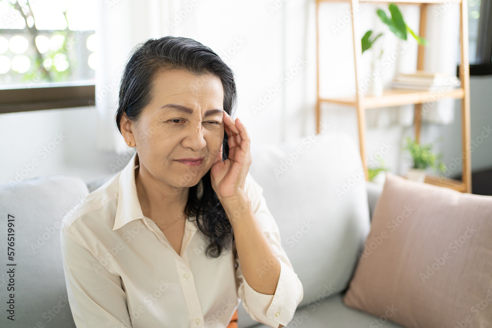 Middle age Asian woman touching forehead having headache suffering from. migraine feeling sick or depression Middle age Asian woman touching forehead having headache suffering from. migraine feeling sick or depression