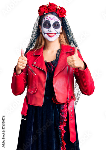 Woman wearing day of the dead costume over background success sign doing positive gesture with hand, thumbs up smiling and happy. cheerful expression and winner gesture.