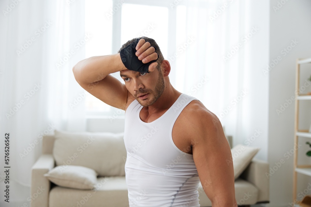 Man sports home training on the floor on a mat with dumbbells, exercises for muscle growth, pumped up man fitness trainer exercises at home, the concept of health and beauty of the body Man sports home training on the floor on a mat with dumbbells, exercises for muscle growth, pumped up man fitness trainer exercises at home, the concept of health and beauty of the body