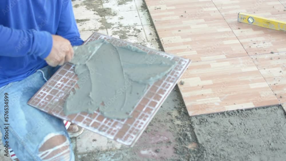 laying ceramic wood tiles on floor, installing tiles in construction site. Stock ビデオ Adobe Stock