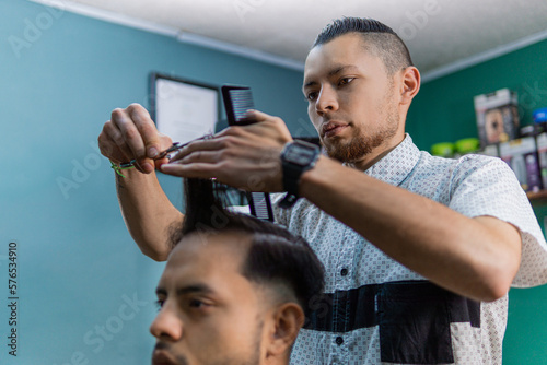 Barber cutting Latin man's hair with scissors