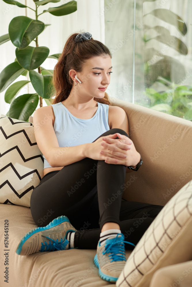 Pensive young woman resting on couch at home