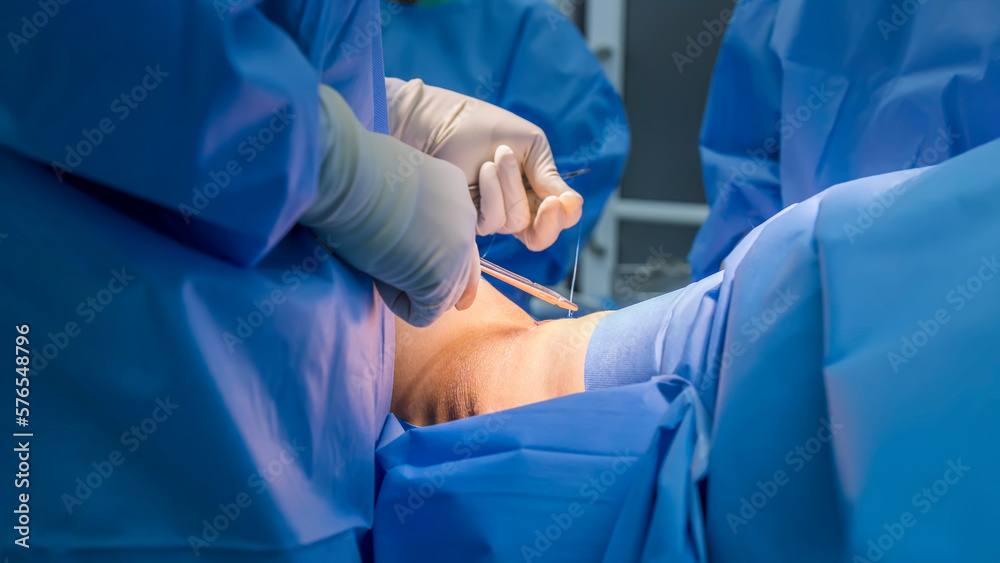 Doctor in blue uniform do surgery inside operating room in orthopedic hospital.Surgeon made suture on skin.Surgeon hold medical equipment to do surgery in operating theatre with space.Medical concept. Doctor in blue uniform do surgery inside operating room in orthopedic hospital.Surgeon made suture on skin.Surgeon hold medical equipment to do surgery in operating theatre with space.Medical concept.
