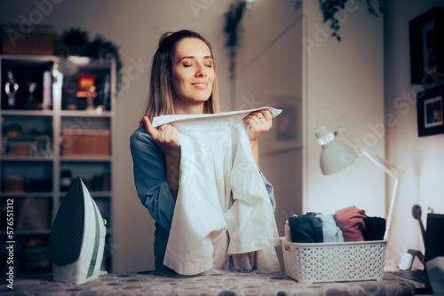 Happy Woman Smelling a Clean Freshly Washed Shirt. Happy housewife enjoying the scent of the fabric conditioner 
