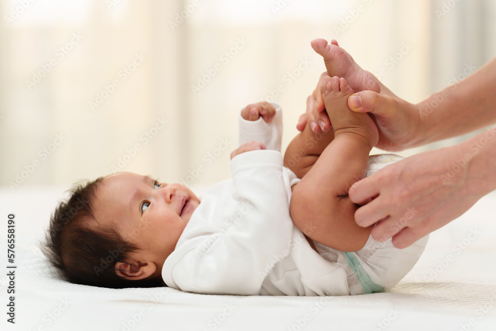 mother changing diaper of newborn baby while lying on bed mother changing diaper of newborn baby while lying on bed