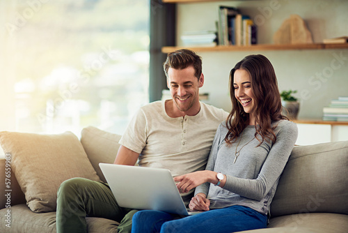 Sharing an online world. Shot of a happy young couple using a laptop together on the sofa at home.
