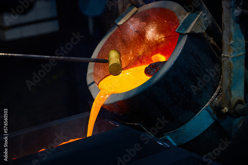 Pouring red liquid silver from bucket in induction oven