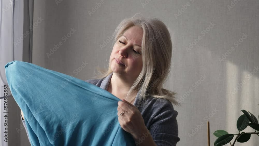 beautiful blonde 45-50 years old hangs fresh washed linen on the dryer while at home. European housewife enjoys the cleanliness of linen. woman's household chores beautiful blonde 45-50 years old hangs fresh washed linen on the dryer while at home. European housewife enjoys the cleanliness of linen. woman's household chores