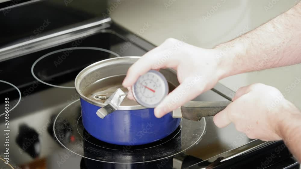 Checking the temperature of melted wax used for homemade candle making