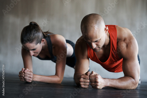 Push your way to fitness. Shot of a man and woman doing plank exercises at the gym.