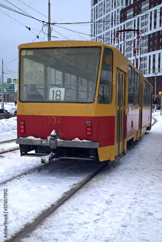 A city tram rides on snow-covered rails on a winter day