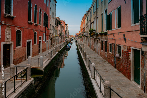 A canal in venice with a red building and a blue sky © Andrey
