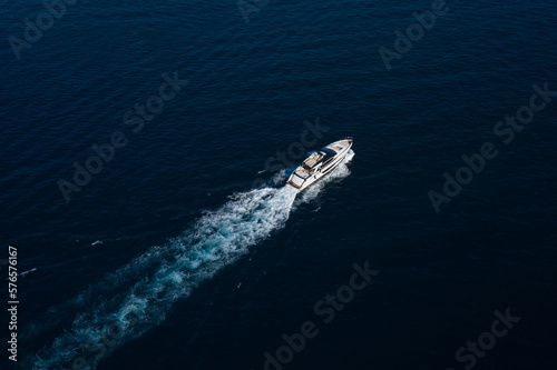 Large open white yacht moves diagonally on dark blue water top view. © Berg