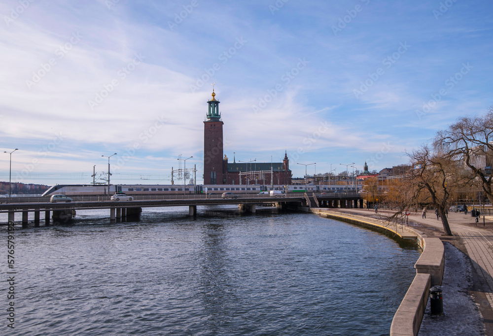 Train and motor way bridge, pier walkway and skyline with the Town City Hall, an early spring sunny day in Stockholm
