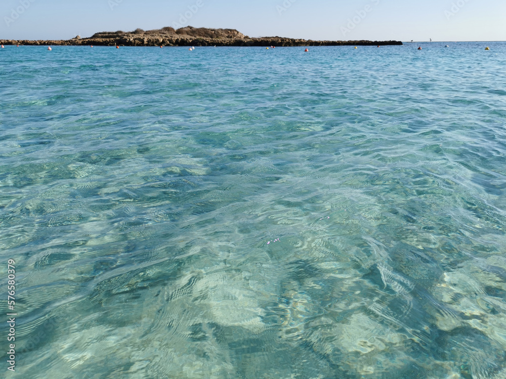 Obraz premium Fig Tree Bay beach, crystal clear water, white sand at the bottom, small island off the coast.