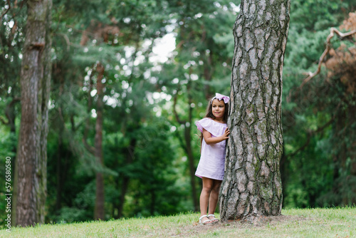 Portrait of cute little child girl hugging tree in the park summer