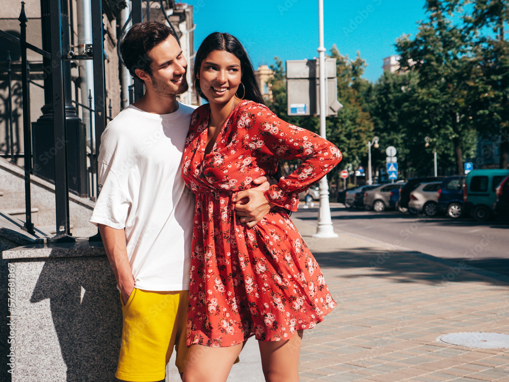 Naklejka premium Smiling beautiful woman and her handsome boyfriend. Happy cheerful family. Sexy couple posing in the street at sunrise. During romantic date at sunny summer day outdoors. Looking at each other