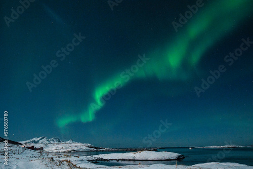 Bright Green Colours of the Northern Light, Aurora Borealis illuminate the Night Sky over the beach at Mjelle, in Arctic Norway.