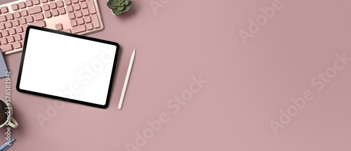 Digital tablet, keyboard, coffee cup and potted plant on pink background. Copy space for text information or content