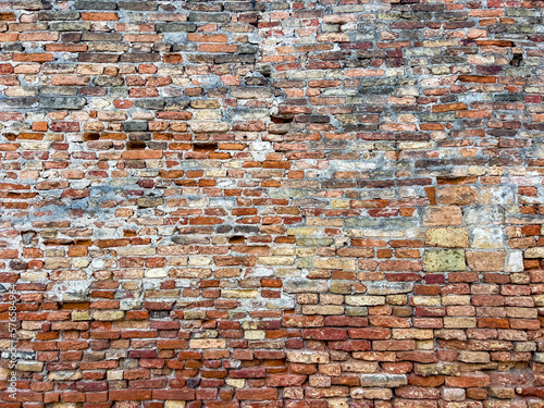 Old slewed traditional brick textured wall background in design loft style. Grunge reddish brown colored with copy space. Blank poster or wallpaper surface template. Partly damaged pattern.