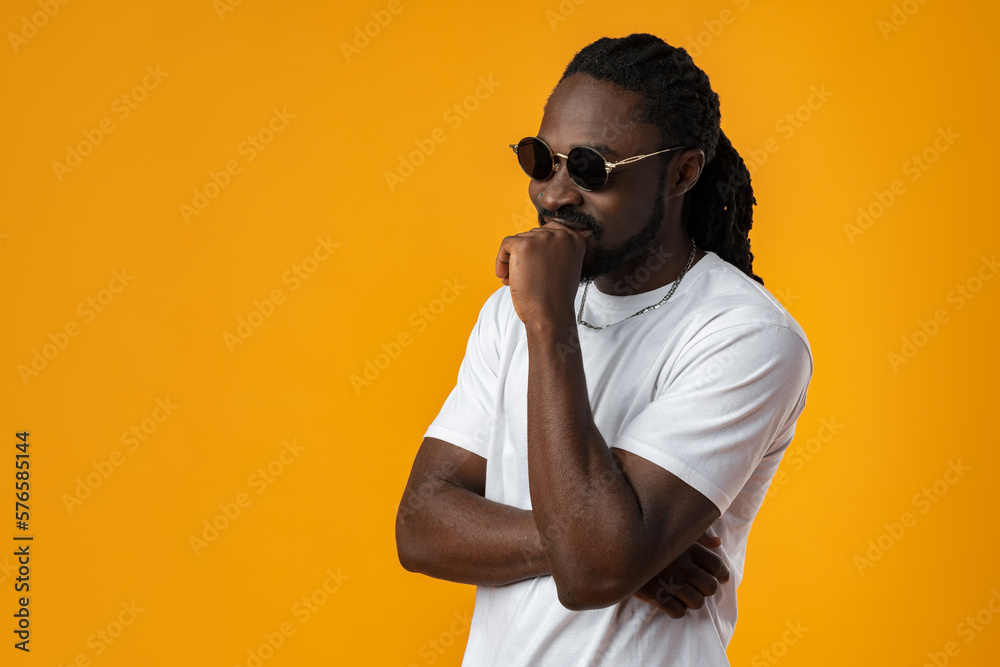 Close up of young african man in sunglasses standing against yellow background Close up of young african man in sunglasses standing against yellow background