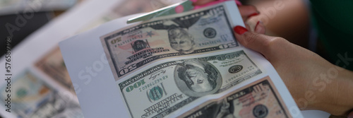 Obraz na plátně Counterfeiter cuts dollar bills with scissors closeup