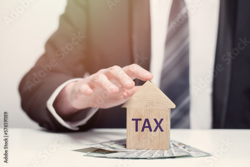 Wooden houses with words tax and double tax, business tax concept, us dollars banknotes in business person hands