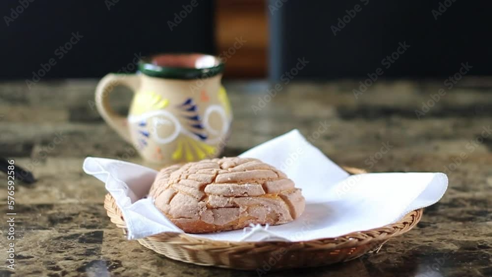 person serving traditional mexican breakfast with chocolate and vanilla bread in front of cup of coffee. shell