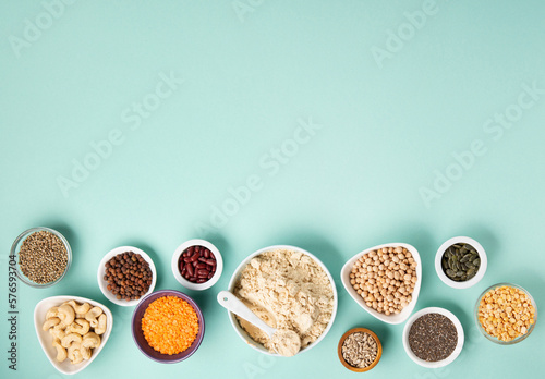Healthy Dry Pea Protein Powder and Plant Based Protein Food (legumes, lentils, beans, seeds) on Blue Green Background.
