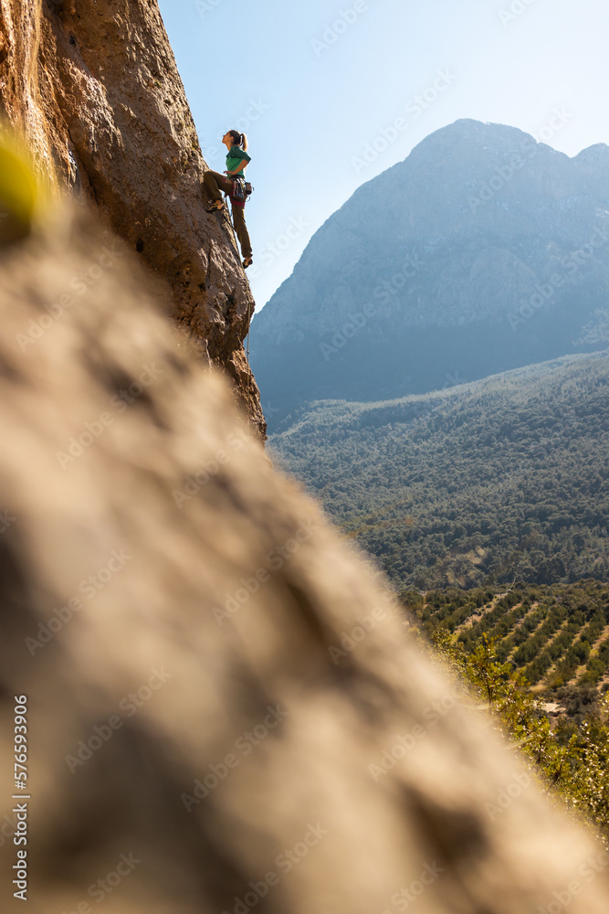 The girl climbs the rocks against the background of the sky and mountains. sports girl is engaged in rock climbing.