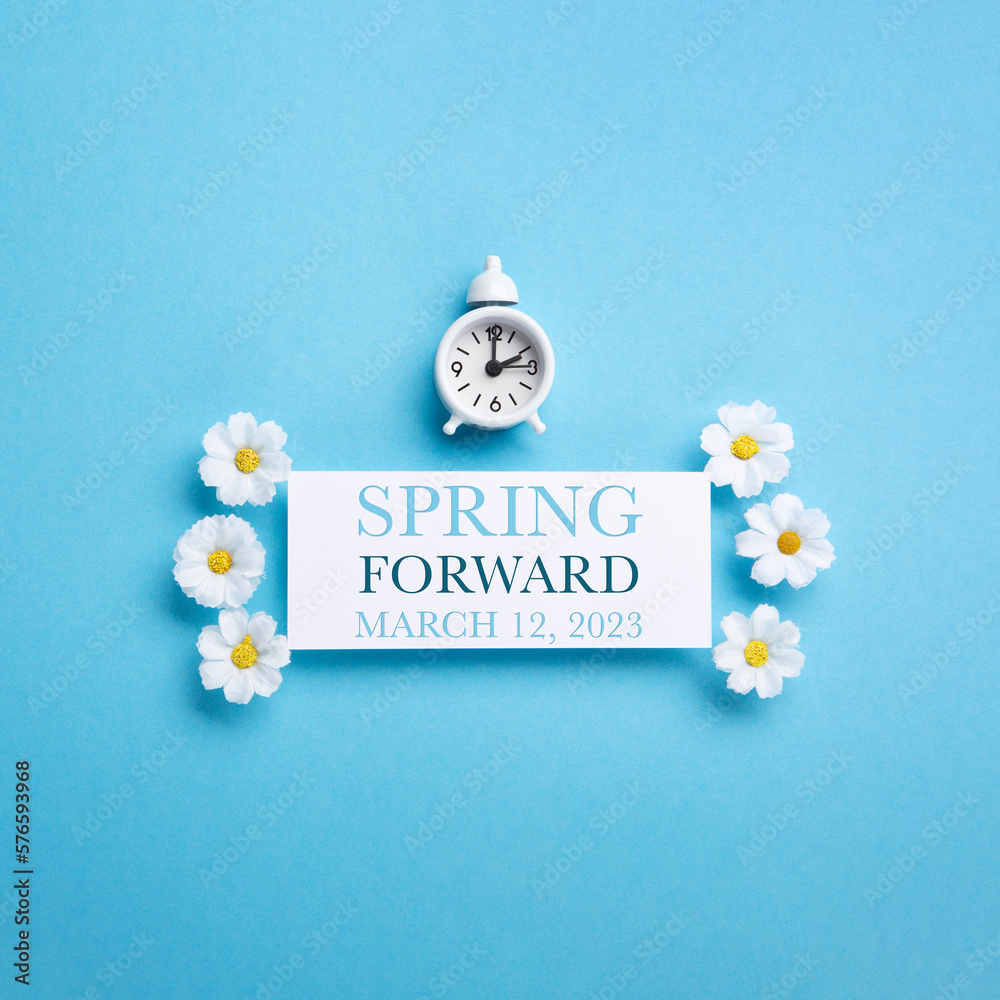 White Alarm Clock and Spring Daisy Flowers on Blue Background - obrazy, fototapety, plakaty 