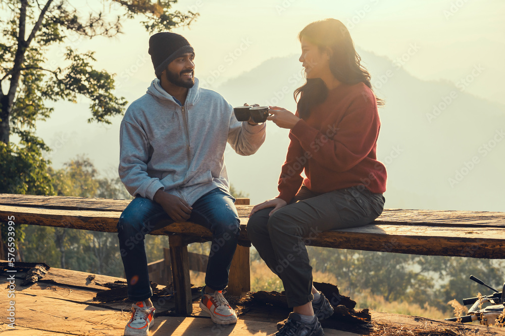 Happy traveler couple resting on mountains in sunrise with drinking coffee - obrazy, fototapety, plakaty 