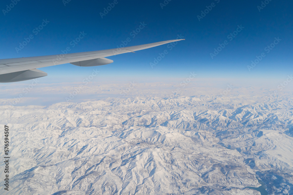 Wing of an airplane jet flying above clouds with blue sky from the window in traveling and transportation concept. Nature landscape background. Wing of an airplane jet flying above clouds with blue sky from the window in traveling and transportation concept. Nature landscape background.